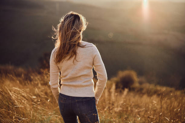 Rear view of a woman standing on a hill and looking at view in autumn day. Copy space.
