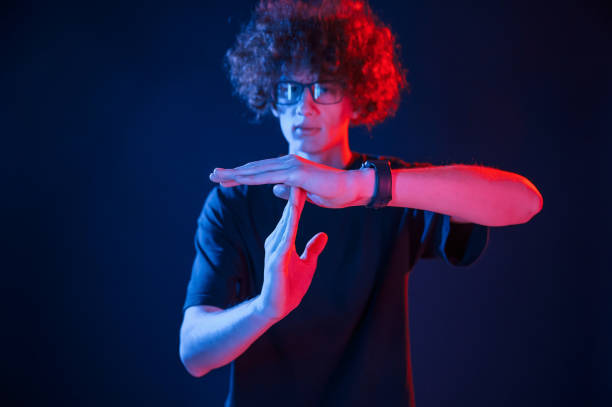 istock Hands gesture. Young man with curly hair is indoors illuminated by neon lighting 1457980146