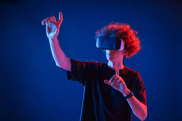 istock Virtual reality experience. Young man with curly hair is indoors illuminated by neon lighting 1457982009