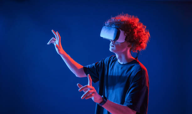 istock Virtual reality experience. Young man with curly hair is indoors illuminated by neon lighting 1457982041