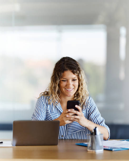 istock Happy businesswoman using cell phone in the office. 1457982819
