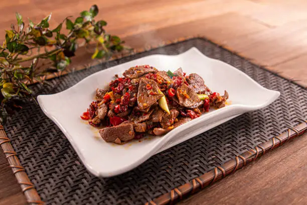 Photo of Spicy Stir-fried Pork Liver served dish isolated on wooden table top view of Hong Kong food