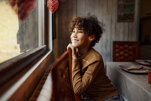 istock Happy black boy looking through window from home. 1457985260
