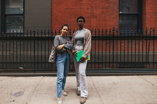 West Village, New York, two multi ethnic friends in the city streets looking at camera.