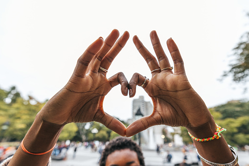 Black woman hands close-up making a heart shape.