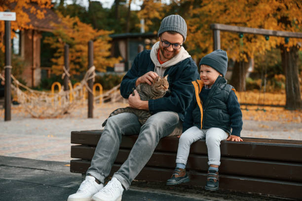 istock Sitting with cute cat. Father and young son is together outdoors at daytime 1457993101