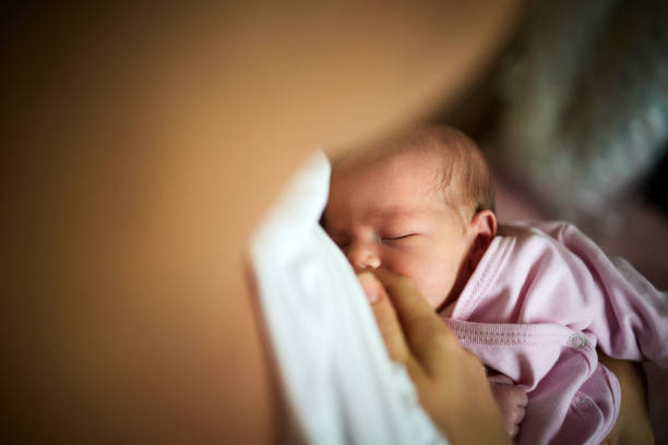 Breastfeeding of newborn baby! Close up of newborn baby girl being breastfed during her sleep. nursing room stock pictures, royalty-free photos & images
