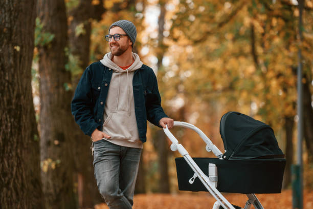 istock Front view. Man with pram is having a walk in the autumn park 1457994383