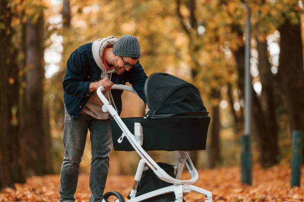 istock Looking inside the pram. Man is having a walk in the autumn park 1457994815