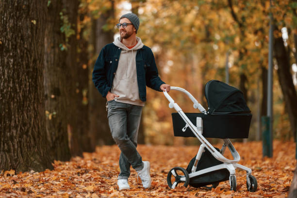 istock Front view. Man with pram is having a walk in the autumn park 1457994827
