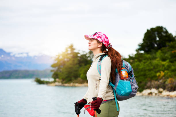 young adult caucasian backpacker woman with eyes closed and head raised enjoy the feeling of being surrounded by nature in Torres del Paine national park stock photo
