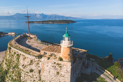 Aerial panoramic drone view of Old Venetian Fortress of Corfu, Palaio Frourio, Kerkyra old town, Greece, Ionian sea islands, with the lighthouse, church and scenery beyond the city in summer sunny day