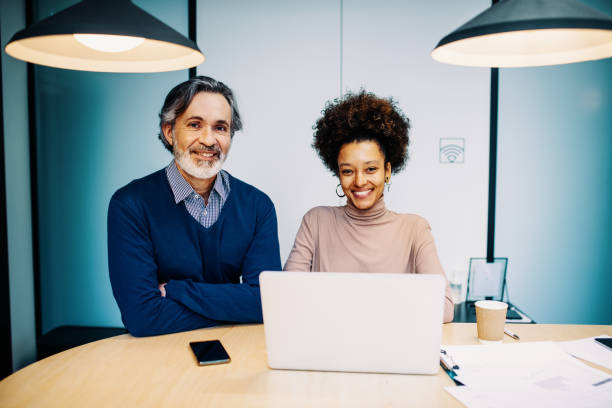 istock Business people in office. Two mature entrepreneurs working together, brainstorming and using laptop 1458001314