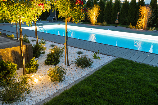 Scenic Residential Outdoor Swimming Pool Illuminated by LED Lighting. Poolside Surrounding Theme.