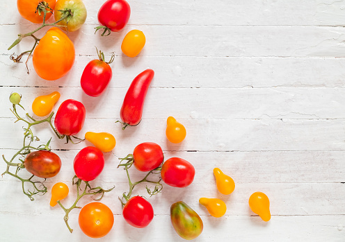 Fresh organic red and yellow tomatoes on a white wooden background. Copy space. Top view.