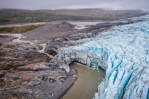 aerial view of waterfalls and tunnel under the ice at Russell Glacier in a cloudy day, Greenland