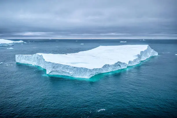 aerial view of a giandt iceberg floating in the arctic sea nearIlulissat Icefjord in a cloudy day, Greenland