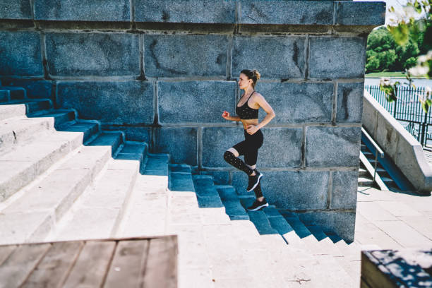 istock Fit woman in active wear training stamina while running upstairs at outdoors stadium 1458003692