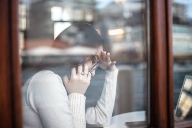 istock Young woman is talking on her mobile phone behind the window. 1458005426