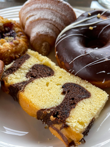 Stock photo showing close-up, elevated view of breakfast pastries and cakes on a white plate.