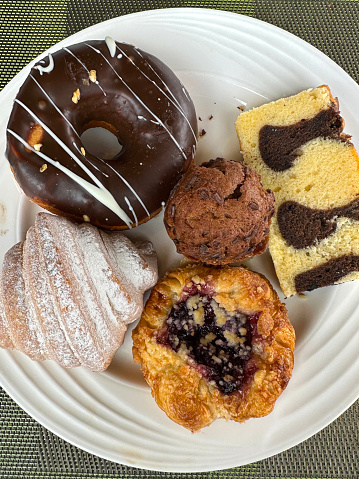 Stock photo showing close-up, elevated view of breakfast pastries and cakes on a white plate.