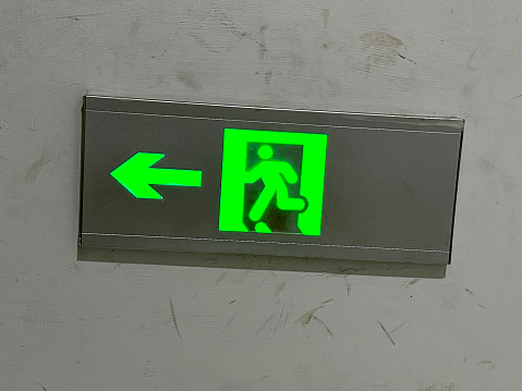 Stock photo showing close-up view of a wall mounted. illuminated emergency fire exit sign.