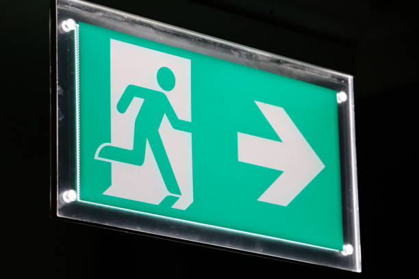 istock Close-up image of clear acrylic 'Fire Exit' sign, acrylic green fire exit wall mounted sign, black background, focus on foreground 1458008674