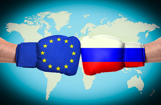 Men in boxing gloves with European union and Russian flags fighting with world map on background, closeup. Political feud