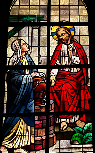 Kalety Miotek, Poland, January 1, 2023: Stained glass windows in the church of St. Francis, seen from the outside in the evening. Jesus with the woman at the well. Living water.