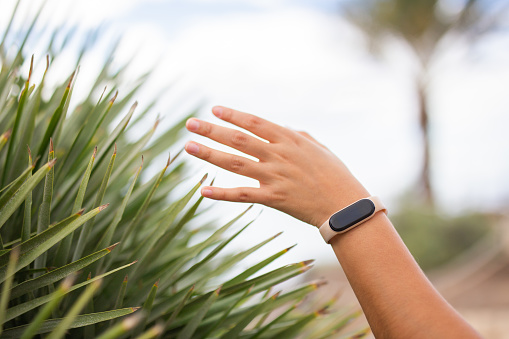 Women's hands touching grass with smartwatch