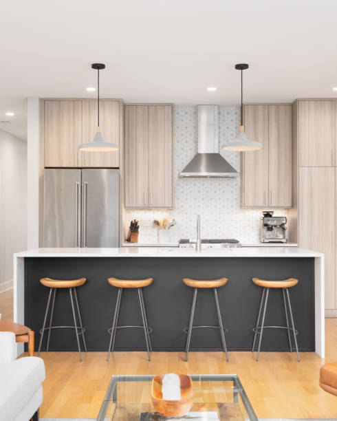 A modern kitchen with wood cabinets, grey island, and tiled backsplash.
