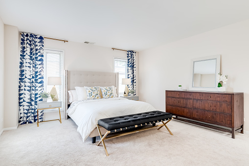 A bedroom with a bench seat, large bed and dresser with nightstands on each side.