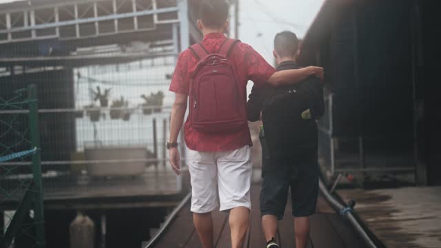 Rear view Asian Chinese Father walking with down syndrome son in Penang famous tourist spot