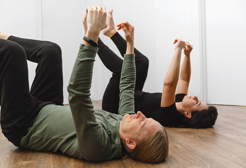 Rehabilitation exercise. Physical therapy concept. Two people laying on the back on the floor with hands and legs up, lymph and blood flow improvement. Feldenkrais method