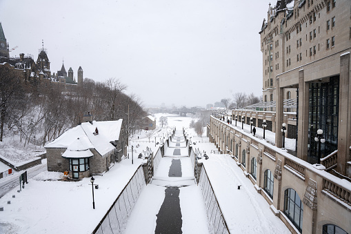 Looking down snow covered Rideau Canal in winter with Parliament Hill and Gatineau in the background