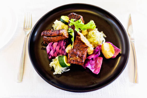 Fine dining restaurant meal of grilled pork fillet served with red cabbage, sauerkraut, zucchini, potatoes and a sauce made from shredded apples