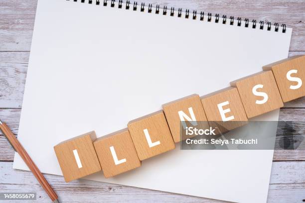 Wooden Blocks With Illness Text Of Concept A Pen And A Notebook Stock Photo - Download Image Now