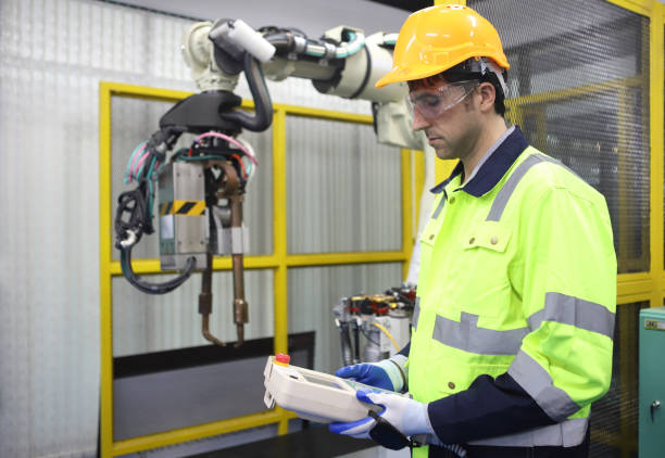 istock engineer teaching robot welding machine , he explanation how to working of robot arm , all function is controlled by remote 1458056643