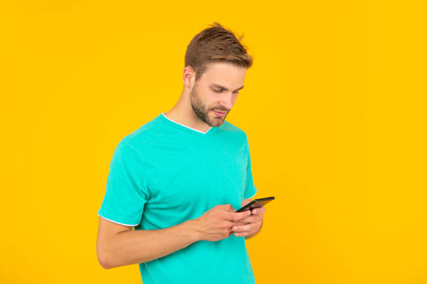 istock guy with bristle chatting on smartphone on yellow background, technology 1458056773