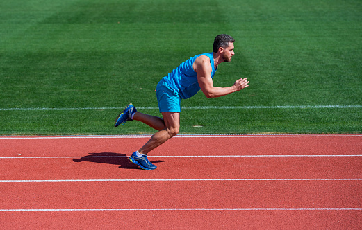 athletic muscular man running in sportswear on stadium track, finish.
