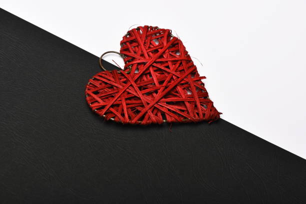 Valentines day and love concept. Woven heart ornament in red colour. Handmade decoration on black and white background.