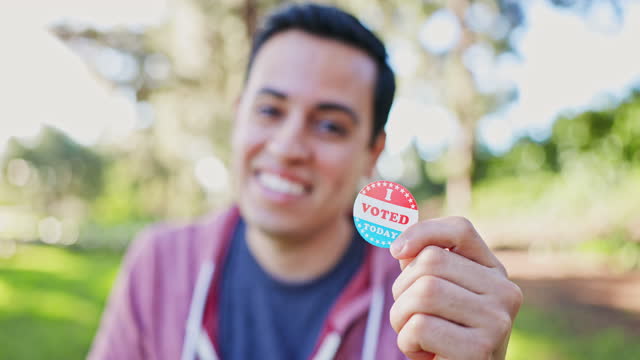 Young Mixed race hispanic man holding an I Voted Sticker