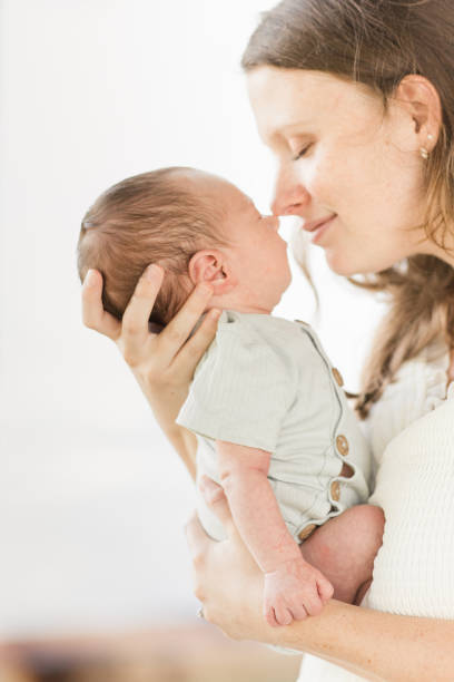 istock A Young Mother Holding Her Newborn Son Relaxed & Enjoying QualityTime Snuggling Her Boy While in a Stone Gazebo on the Water in a Relaxing Meditation Garden in Palm Beach, Florida for Lifestyle Newborn Family Photos 1458070773