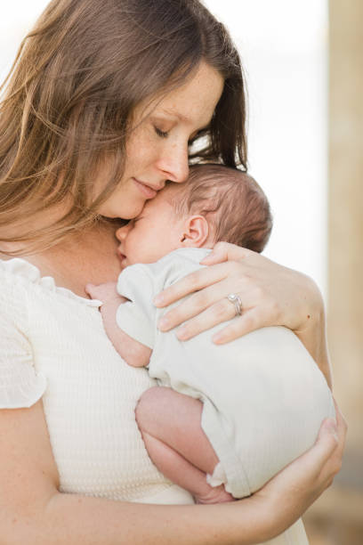 istock A Young Mother Holding Her Newborn Son Relaxed & Enjoying QualityTime Snuggling Her Boy While in a Stone Gazebo on the Water in a Relaxing Meditation Garden in Palm Beach, Florida for Lifestyle Newborn Family Photos 1458070882