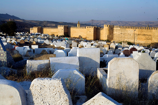 Looking at the walls of the city of Fez, through the grace stones of a cemetery.