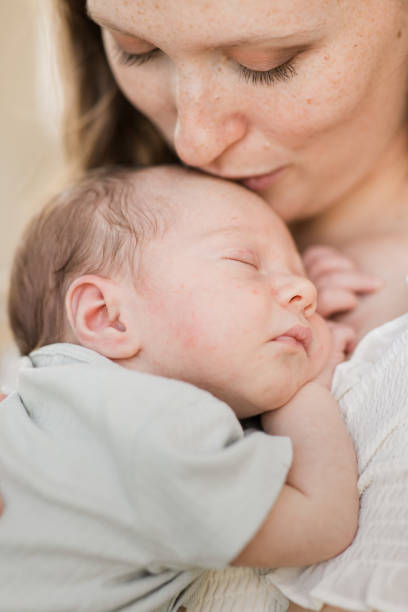 istock A Young Mother Holding Her Newborn Son Relaxed & Enjoying QualityTime Snuggling Her Boy While in a Stone Gazebo on the Water in a Relaxing Meditation Garden in Palm Beach, Florida for Lifestyle Newborn Family Photos 1458072230