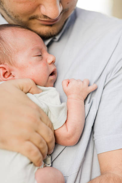 istock A Sweet Young Father Holding His Newborn Son While Standing Relaxed & Enjoying QualityTime Together in a Stone Gazebo on the Water in a Relaxing Meditation Garden in Palm Beach, Florida for Lifestyle Newborn Family Photos 1458073203