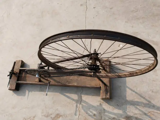 Photo of hand loom machine making thread on Charkha the spinning wheel in village at Varanasi, India. weaver prepares threads to make fabric with a handloom, spins yarn on an old fashioned spinning wheel.