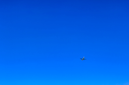 Airplane flies past clear blue sky in Germany.