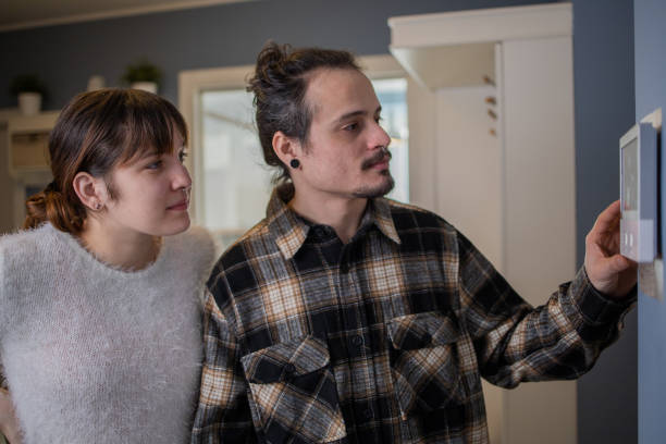 istock Young man adjusts the temperature at home with a device on the wall 1458076070